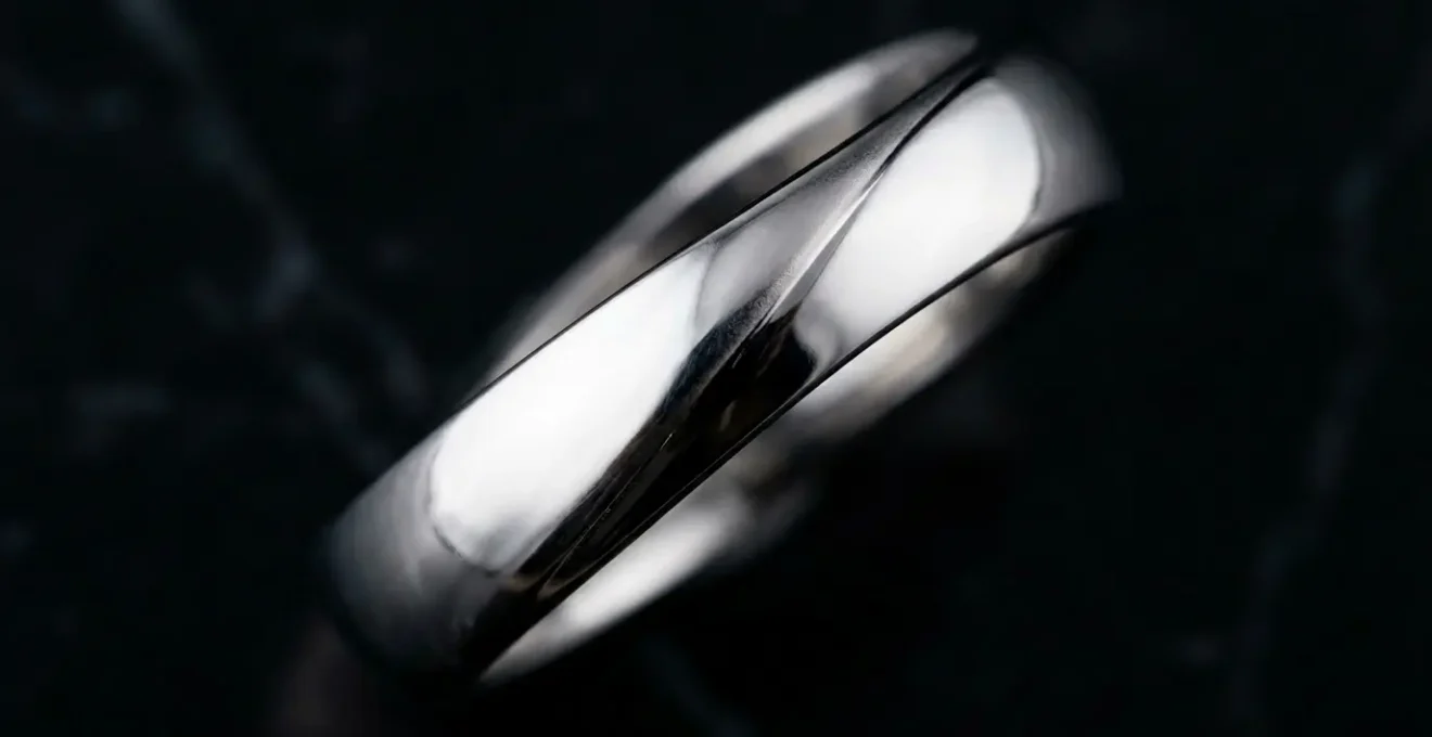 Bague en argent rhodié brillante sur surface en marbre noir avec reflets lumineux