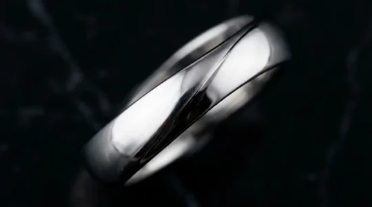 Bague en argent rhodié brillante sur surface en marbre noir avec reflets lumineux