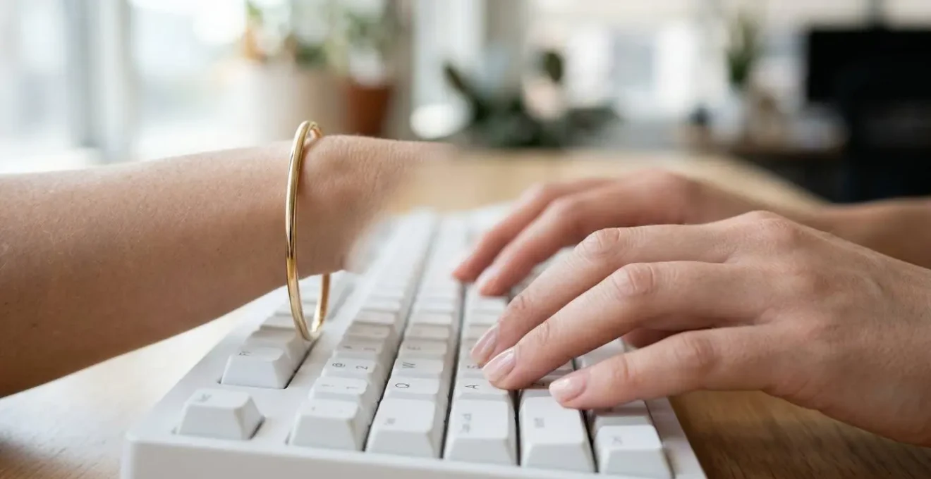 Gros plan sur des mains féminines tapant au clavier avec bracelet jonc fin en or