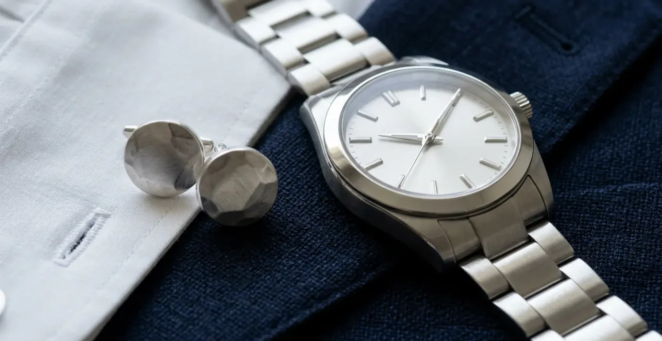 Gros plan sur une montre en acier et des boutons de manchette harmonisés avec un costume bleu élégant