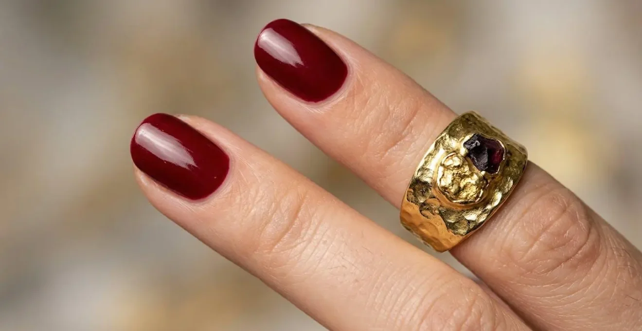 Gros plan sur des mains manucurées avec vernis rouge et bague en or